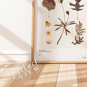 May include: A framed botanical print with pressed autumn leaves and flowers. The print is titled "Herbarium Autumn Collection" and is dated 2021. The print is displayed on a light wood floor.