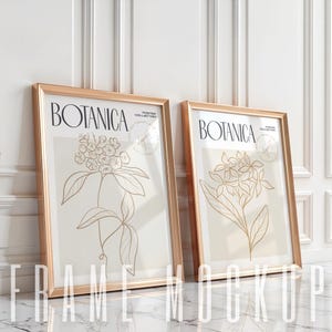 May include: Two gold framed posters with white backgrounds and gold line drawings of flowers. The posters have the text "Botanica Poster Collection" on them.