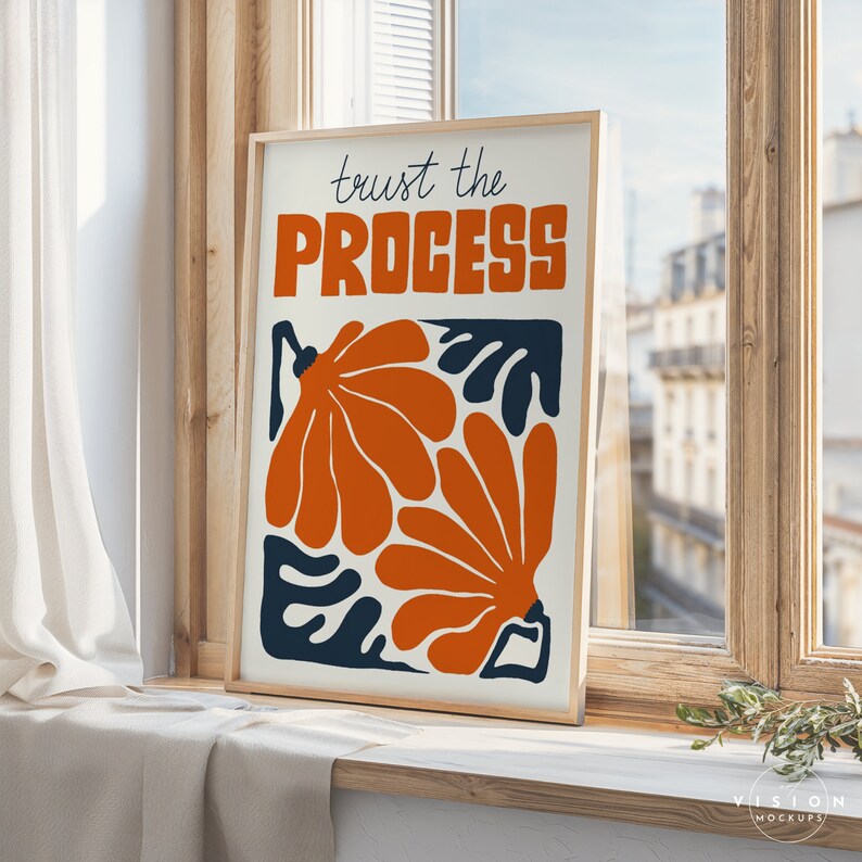 May include: A framed print with a white background and the text "trust the PROCESS" in blue lettering. The print features an abstract design of orange and blue shapes.
