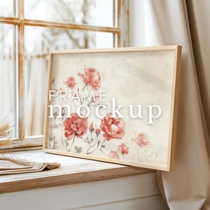 May include: A framed print featuring a watercolour painting of pink roses on a beige background. The frame is made of light wood and the print is leaning against a white wall.