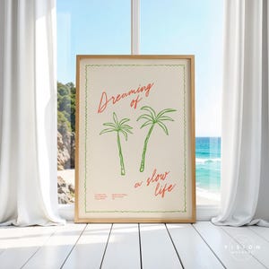 May include: A framed print with a white background and green palm trees. The text "Dreaming of a slow life" is written in red cursive.