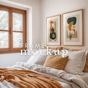 May include: Two abstract art prints in wooden frames hang above a bed with white bedding and a mustard yellow throw blanket. The prints feature geometric shapes in shades of orange, yellow, green, and brown.