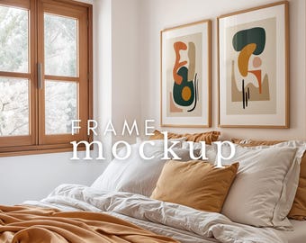 May include: Two abstract art prints in wooden frames hang above a bed with white bedding and a mustard yellow throw blanket. The prints feature geometric shapes in shades of orange, yellow, green, and brown.