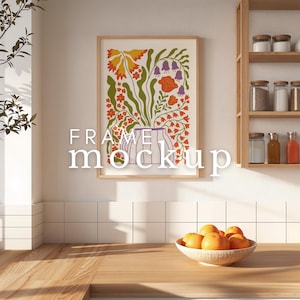 Puede incluir: Una impresión enmarcada de una ilustración floral colorida con un jarrón de flores en el centro. La impresión está colgada en una pared blanca alicatada en un ambiente de cocina. Un bol de naranjas se encuentra sobre una encimera de madera en primer plano.