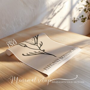 May include: A minimalist poster with a black line drawing of a flower on a beige background. The text "Elegant Botanica" is printed in black at the bottom of the poster. The poster is rolled up and sitting on a wooden surface.
