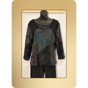 May include: A long-sleeved top with a unique patchwork design. The top features a mix of patterned fabrics in shades of black, purple, and teal. The neckline and sleeves are solid black, and the garment is displayed on a mannequin.