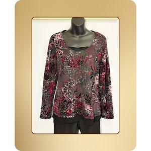 May include: A long-sleeved top with a floral pattern in shades of gray, burgundy, and black. The top has a scoop neckline and is displayed on a mannequin. The bottom portion of the outfit is black.