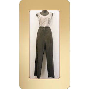 Pode incluir: Um conjunto de duas peças em um manequim. A parte superior é uma blusa bege clara sem mangas. As calças são marrons escuras com listras verticais e um design de perna larga. O conjunto é exibido em um fundo neutro.