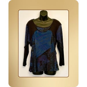 May include: A long-sleeved top with a unique patchwork design. The top features a dark brown yoke and sleeves, with a central panel in shades of blue and black. The fabric has a subtle sheen, and the overall style is artistic and flowing.