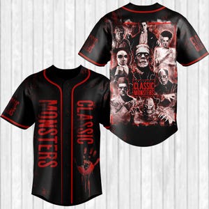 May include: Black baseball jersey with red trim and the words "CLASSIC MONSTERS" in red. The front features a handprint and the back displays classic monster portraits. The sleeves also have the words "CLASSIC MONSTERS".