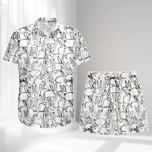 Puede incluir: Conjunto de camisa y pantalón corto blancos con un estampado repetido de conejos en blanco y negro. El pantalón corto tiene cintura con cordón. La camisa tiene mangas cortas y cuello.