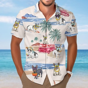 Könnte beinhalten: Weißes kurzärmeliges Hemd mit einem sich wiederholenden Muster von französischen Bulldoggen am Strand. Die Hunde tragen Sonnenbrillen und Blumenketten, mit Palmen, einem roten Van und Strandszenen. Das Hemd hat eine lockere Passform.