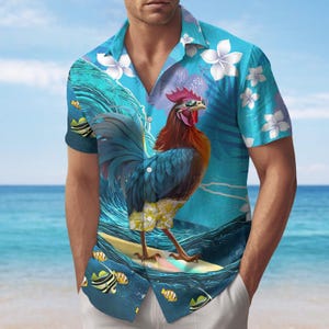 Puede incluir: Una camisa de manga corta con un diseño tropical. La camisa presenta un gallo surfeando en una tabla de surf, sobre un fondo de olas oceánicas y flores tropicales. La paleta de colores incluye tonos de azul, verde y amarillo.