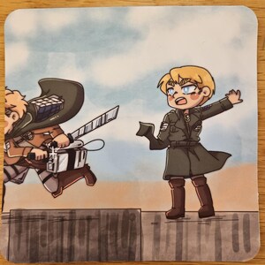 Puede incluir: Un posavasos cuadrado con una ilustraci&oacute;n de estilo anime de dos personajes en acci&oacute;n. Uno corre con una espada, el otro est&aacute; de pie sobre un muro. El fondo es un cielo azul claro.