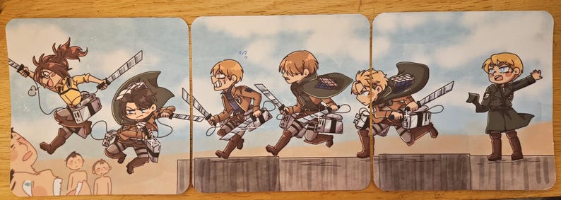 Puede incluir: Un conjunto de tres tarjetas cuadradas con ilustraciones de dibujos animados de personajes de la serie de anime Attack on Titan. Los personajes se muestran en acci&oacute;n, con espadas y uniformes militares, sobre un fondo de cielo azul.