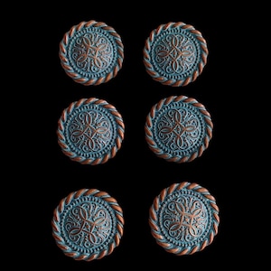 Op de afbeelding: Zes ronde, decoratieve knoppen met een koperkleurige touwrand en een turquoiseblauw centrum. Het midden van elke knop heeft een reliëf, ingewikkeld, bloemmotief.