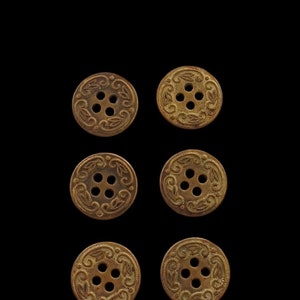 Op de afbeelding: Zes antiek ogende gouden knopen met een decoratief bloemmotief en vier gaten.