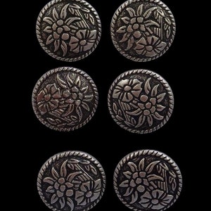 May include: Six silver-toned metal buttons with a floral design. Each button features a stylized flower with a center circle and surrounding petals.