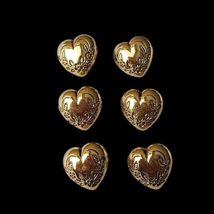 Könnte beinhalten: Sechs goldfarbene herzförmige Knöpfe mit floralem Muster. Die Knöpfe haben einen Durchmesser von etwa 2,5 cm.