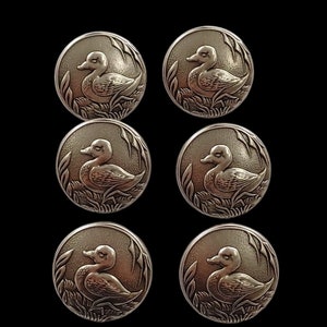 Könnte beinhalten: Sechs silberfarbene Metallknöpfe mit einem erhabenen Design eines Entchens in einer Teichumgebung.