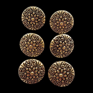 Könnte beinhalten: Sechs goldfarbene Metallknöpfe mit Blumenmuster. Jeder Knopf hat eine erhabene Mitte mit einem kleineren Blumendesign, das von einem größeren Blumendesign umgeben ist.