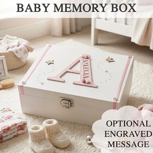 May include: A white baby memory box with pink trim, a large pink letter 'A' with the name 'Amelia', and butterfly decorations. The box has a silver clasp and the text 'BABY MEMORY BOX' is at the top.