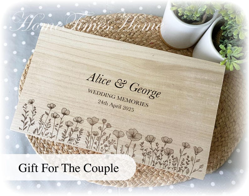 Pu&ograve; includere: Una scatola di legno chiaro con i nomi "Alice & George" e la data "24 aprile 2025" incisi. La scatola &egrave; decorata con un bordo floreale e il testo "Gift For The Couple".