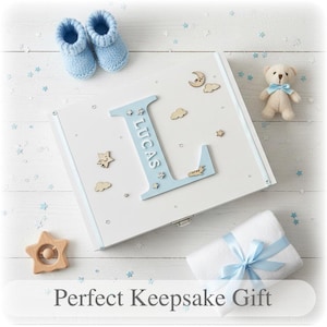 Peut inclure: Coffret souvenir blanc avec un "L" bleu clair et le nom "Lucas". La bo&icirc;te est d&eacute;cor&eacute;e d'&eacute;toiles, de nuages et d'une lune en bois. On y trouve aussi des chaussons bleus pour b&eacute;b&eacute;, un ours en peluche, un hochet en forme d'&eacute;toile et une couverture blanche emball&eacute;e.