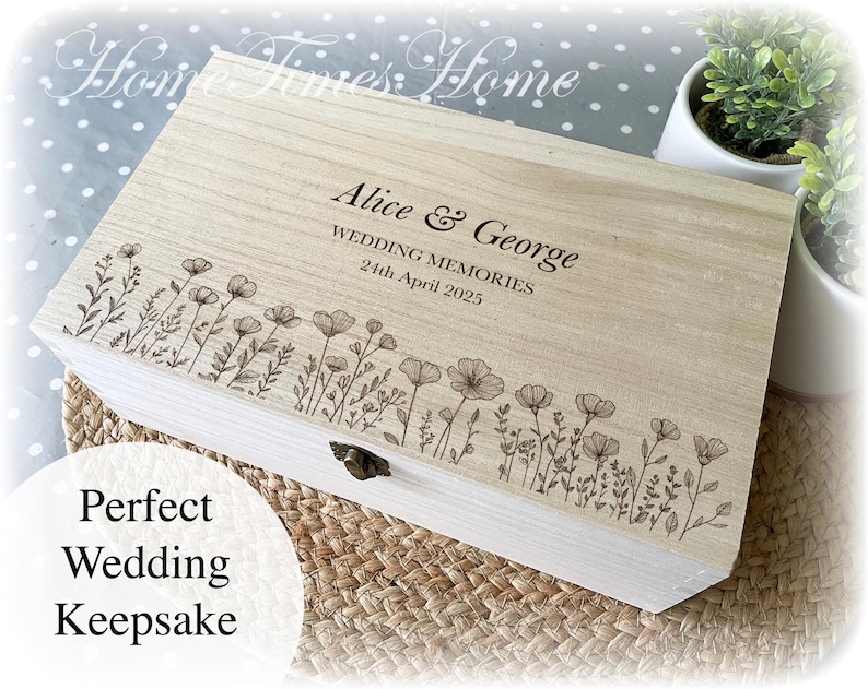 Pu&ograve; includere: Un cofanetto ricordo in legno chiaro con un design floreale e i nomi "Alice & George" incisi sul coperchio. &Egrave; presente anche il testo "WEDDING MEMORIES 24th April 2025". La scatola &egrave; rettangolare con una chiusura in metallo.