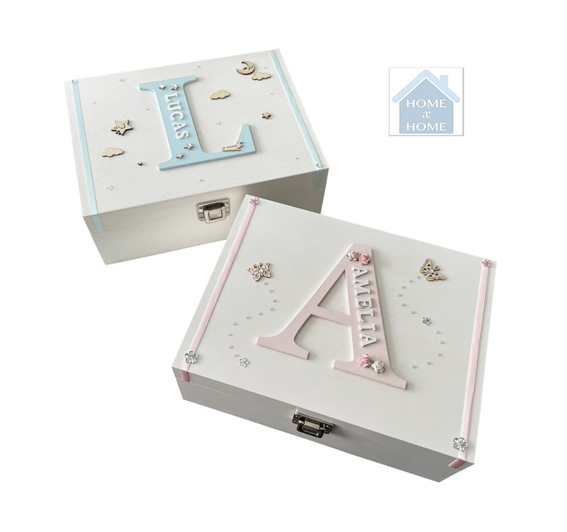 Peut inclure: Deux bo&icirc;tes &agrave; souvenirs en bois blanc, l'une avec un &laquo; L &raquo; bleu et le nom &laquo; LUCAS &raquo;, l'autre avec un &laquo; A &raquo; rose et le nom &laquo; AMELIA &raquo;. Les deux bo&icirc;tes sont d&eacute;cor&eacute;es d'&eacute;toiles, de papillons et de rubans.