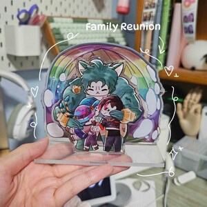 May include: A clear acrylic display featuring a cartoon family reunion scene. The design includes a large green character embracing three smaller figures, set against a rainbow backdrop. The text "Family Reunion" is visible at the top.