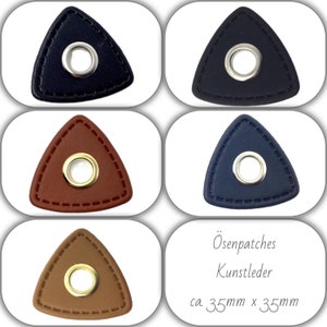 Könnte beinhalten: Vier dreieckige Leder-Patches mit einer Metallöse in der Mitte. Die Patches sind in vier Farben: Schwarz, Braun, Dunkelblau und Hellbraun. Die Patches sind ca. 35 mm x 35 mm groß. Der Text "Ösenpatches Kunstleder ca. 35 mm x 35 mm" steht unter den Patches.