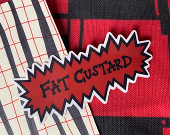 May include: A red and white sticker with a jagged edge and the text "FAT CUSTARD" in black lettering.