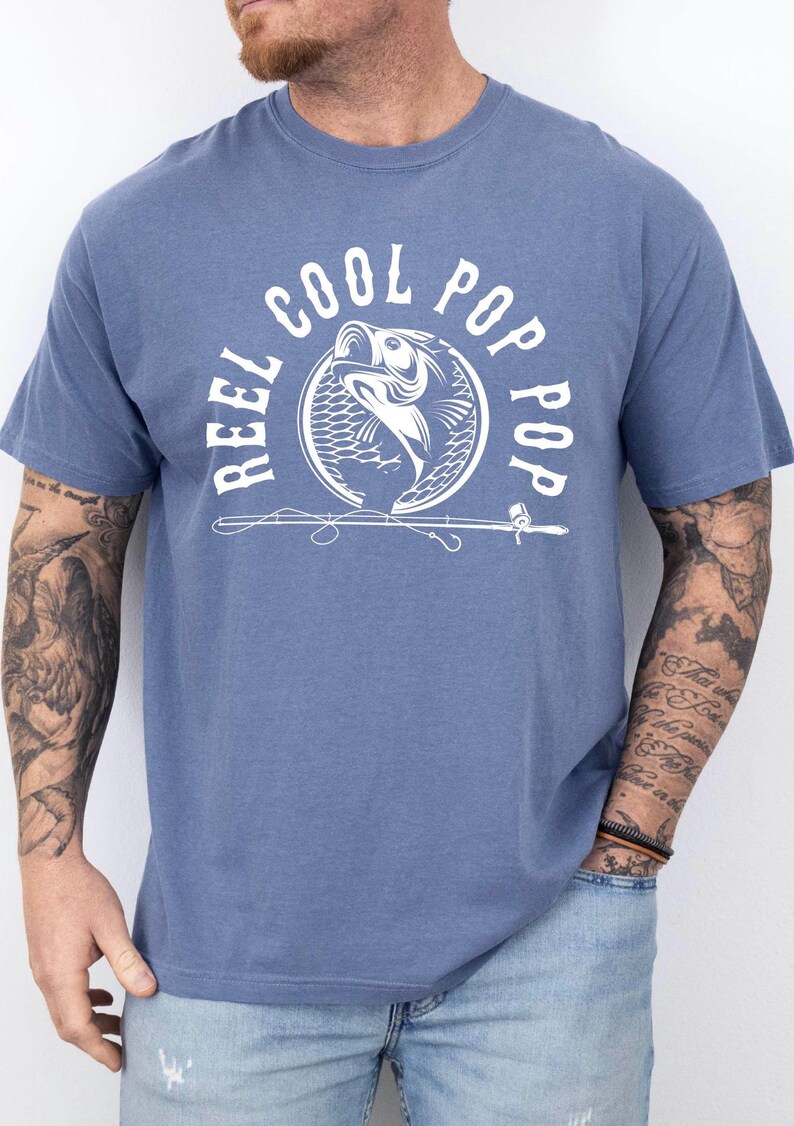 May include: A blue t-shirt with a white graphic of a fish and the text "Reel Cool Pop Pop".