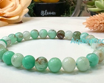 May include: A green gemstone bracelet with round beads. The beads are a mix of light and dark green.