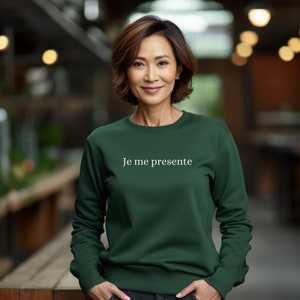 May include: A dark green sweatshirt with the text "Je me presente" in white lettering.