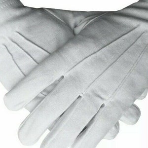 Puede incluir: Un par de guantes de algodón blanco con una textura lisa. Los guantes están doblados por la mitad y los dedos son visibles.