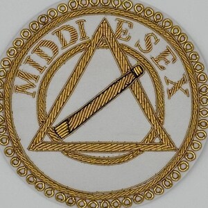 Może przedstawiać: Biała naszywka haftowana ze złotą obwódką i napisem "MIDDLESEX" w kółku wokół trójkąta z złotym prętem w środku.