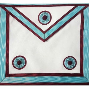 May include: A white Masonic apron with a maroon border and light blue trim. The apron has three rosettes with a maroon center and light blue petals.