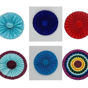 Puede incluir: Seis diseños de rosetas diferentes, cada uno con un esquema de color único. Las rosetas están hechas de tela y tienen una forma circular. Los colores incluyen azul, rojo, turquesa y un diseño multicolor.