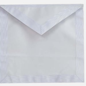May include: A white apron with a textured border and a triangular flap at the top. The apron is rectangular with a smooth, light-colored fabric. The border has a subtle, wood-grain-like pattern.