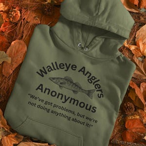 May include: A green hooded sweatshirt with a black graphic print of a walleye fish and the text "Walleye Anglers Anonymous" and the quote "We've got problems, but we're not doing anything about it!"