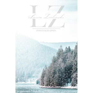 Pode incluir: Uma paisagem nevada com um lago e uma floresta de pinheiros. O texto "LZ Photography" e "Laura Zielinski" est&aacute; no centro superior da imagem.