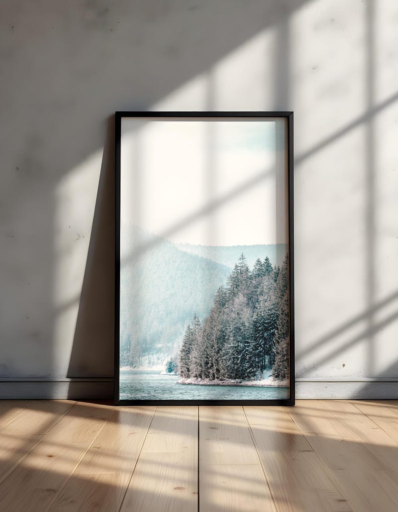 Pode incluir: Uma fotografia emoldurada de uma paisagem montanhosa nevada com um lago em primeiro plano. A foto est&aacute; em uma moldura preta e est&aacute; pendurada em uma parede branca.