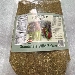 Puede incluir: Una bolsa transparente llena de Za'atar salvaje de Grandma. La etiqueta muestra "ANCIENT TREE" y una ilustración de plantas. Ingredientes: orégano, flor de tomillo, zumaque, semillas de sésamo y sal marina.