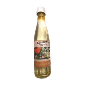 May include: A clear glass bottle with a white cap, filled with a golden liquid. The label reads "ANCIENT TREE" above a picture of an orange fruit and white flowers. Below, it says "Orange Blossom Flower Water".
