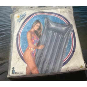 May include: An Intex The Wet Set inflatable pool float in a clear plastic package. The packaging features a graphic of a person in a colorful swimsuit next to a grey, rectangular, multi-chambered air mattress. Dimensions are 72 in x 30 in.