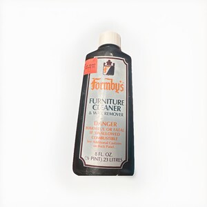 May include: A black bottle of Formby's Furniture Cleaner & Wax Remover. The label includes the brand name, product description, and warning information. The bottle contains 8 fl. oz. (½ pint).