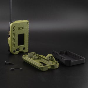May include: An olive green handheld radio with the text "H27" and a small screen. The radio is partially disassembled, with the case components and a screw visible. A black antenna extends from the top.
