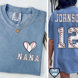 May include: A blue jean t-shirt with a baseball heart and the text "I love Nana" on the front. The back of the shirt has a baseball-themed number 12 with the name "Johnson" above it.